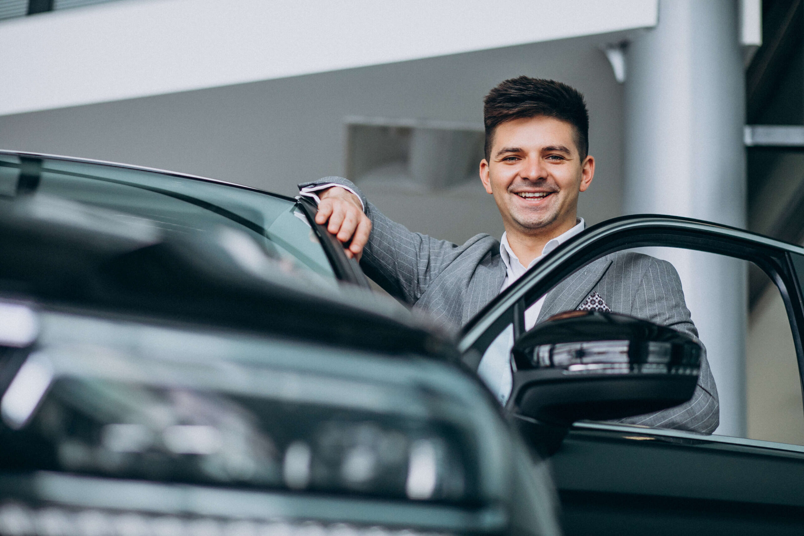 Young handsome business man choosing a car in a car showroom